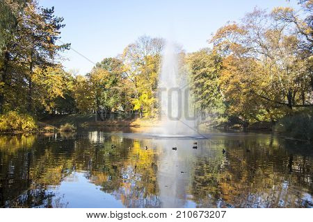 Fountain and rainbow in Riga Canal that flows through Bastion park autumn background with colored leaves (Bastejkalns). Latvia autumn