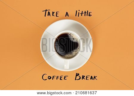 Top view of cup of black coffee and Take a little coffee break lettering isolated on orange background. Still life. Mock up. Flat lay