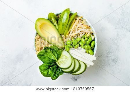 Vegan detox green Buddha bowl recipe with quinoa avocado cucumber spinach tomatoes mung bean sprouts edamame beans daikon radish. Top view flat lay