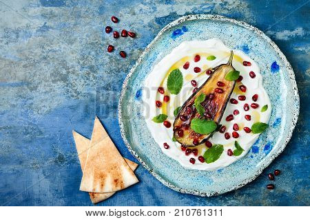 Labneh middle eastern lebanese cream cheese dip with roasted aubergine pomegranate mint and pita. Top view overhead copy space