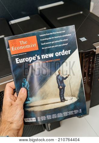 PARIS FRANCE - OCT 20 2017: Man reading The Economist magazine with illustration of Emmanuel macron and A Merkel and Europe's new order