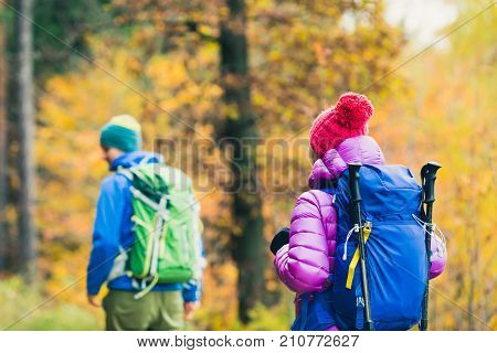 Happy couple hikers trekking in beautiful yellow autumn forest and mountains. Young people man and woman walking on trek trail with backpacks healthy lifestyle adventure camping on hiking trip.