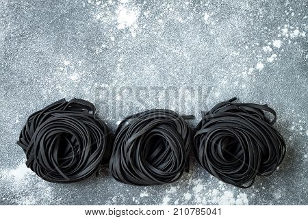 Detox charcoal or black squid ink fettuccine on grey background. Copy space
