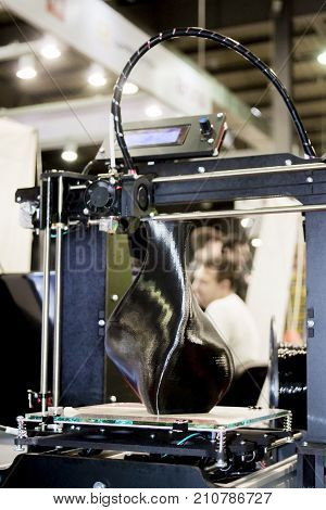 3D printer printing a model in the form of black vase close-up. The concept modern additive technology. The 4ht industrial revolution.