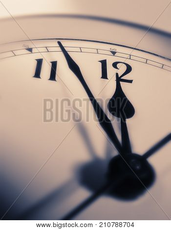 CLOSE UP OF CLOCK FACE WITH HANDS POINTING TOWARDS TWELVE O'CLOCK