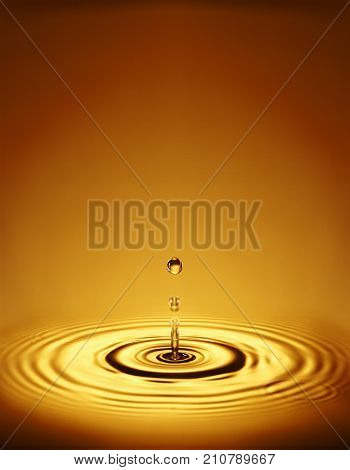 WATER DROPLET MAKING RIPPLES IN COLOURED LIQUID
