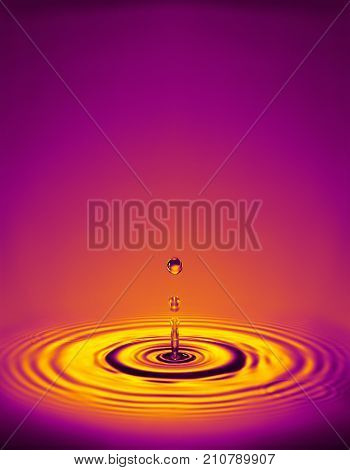 WATER DROPLET MAKING RIPPLES IN COLOURED LIQUID