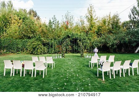Place for wedding ceremony with white chairs and an arch of living plants