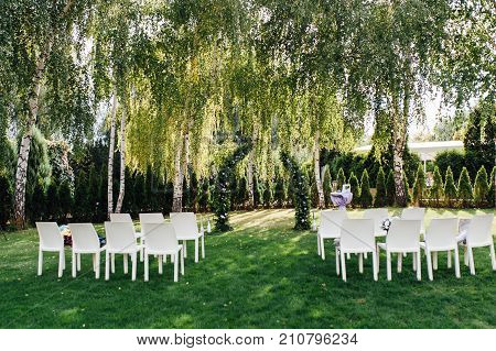 Place for wedding ceremony with white chairs and an arch of living plants