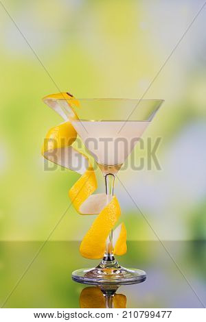 Glasses of cream liqueur with lime and lemon on green background with reflection. Short of lemon liqueur. Traditional Italian alcoholic beverage Limoncello