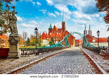 Cathedral Island in Wroclaw Poland green bridge with view on of St John the Baptist picturesque panorama medieval town blue sky and white cloud.