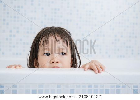 happy funny asian baby laughing and bathed in the bath little asian toddler playing hide and seek in the bath tub