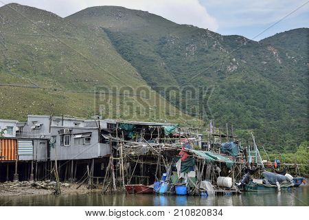 Fishing village Tai O in Hong Kong with traditional pile dwellings and mountains in the background.