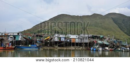 Fishing village Tai O in Hong Kong with traditional pile dwellings and mountains in the background.