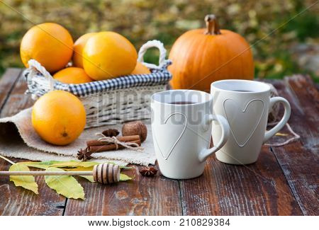 tea with lemon, honey, oranges, autumn leaves on woodenbackground