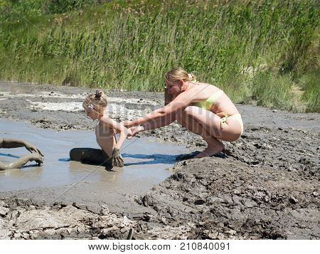 Mother gently bathing my daughter in the mud. Treatment non-traditional methods.