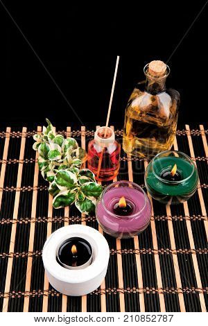 Spa still life with aromatic candles on black background