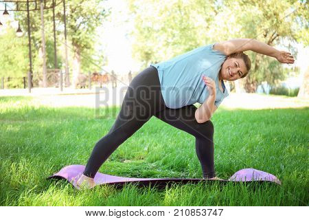 Overweight woman training on green grass