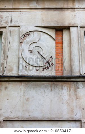 Close up strange stone clock on grey wall in Warsaw, Poland