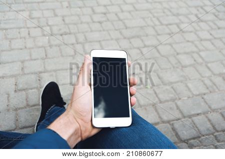 The human hand is using the smart phone. Winter time. Concept waiting or meeting. Outdoor