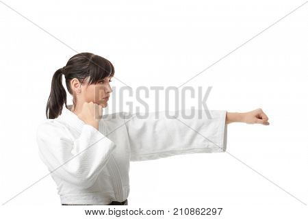 Young woman practicing karate on white background