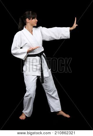 Young woman practicing karate on dark background