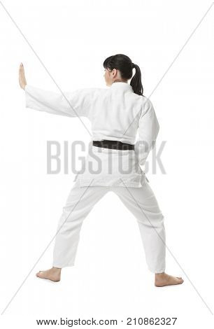 Young woman practicing karate on white background