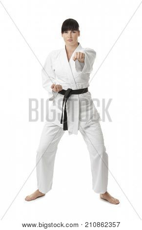 Young woman practicing karate on white background