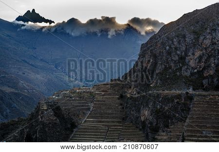 People Walking On The Terraces Of Pumatallis, Ancient Inca Fortress And Mountains Covered In Clouds,
