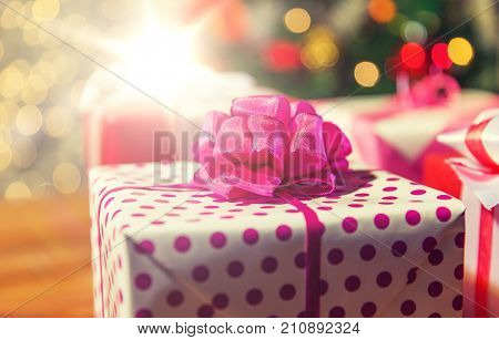 christmas, holidays, presents, new year and celebration concept - close up of gift boxes over christmas tree lights