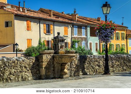 Spectacular colorful traditional Provence houses, decorated street with beautiful flowers and graven water fountain, Moustiers-Sainte-Marie, Provence, France, Europe
