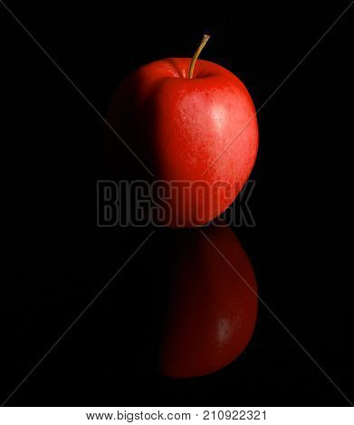 Studio photography of a fresh red apple in black reflective back