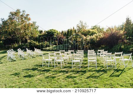 Place for wedding ceremony with white chairs and an arch of living plants