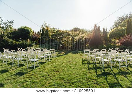 Place for wedding ceremony with white chairs and an arch of living plants