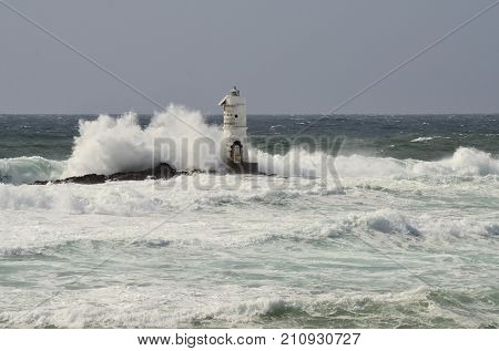 White lighthouse on the cliff. Lighthouse Mangiabarche located in the south of Sardinia. Italy. image colored