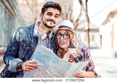 Loving couple with the help of a map looking for an address on the strreet.