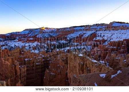 Beautiful Bryce Canyon in Utah with a blanket of snow during sunset.