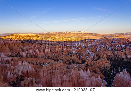 Glowing epic view of Bryce Canyon during sunset in the winter with a light layer of snow in Utah.