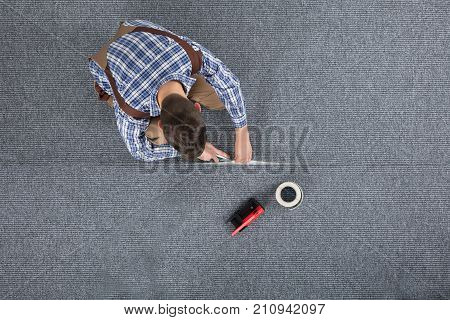 Close-up Of Carpenter Hand's Laying Carpet Using Cutter