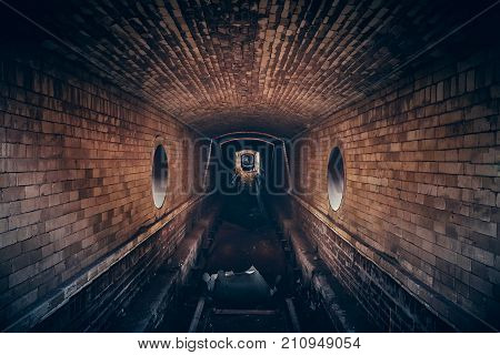 Red brick abandoned underground sewer tunnel with dramatic mysterious atmosphere, inside sewerage, dark toned