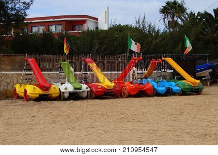 Costa Calma, Fuerteventura, Canary Islands, Spain - October 21, 2017:  Row of colorful paddle boats with slides on the beach of Costa Calma, Spain.