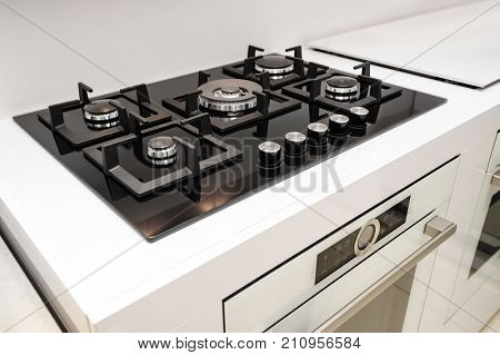 Gas stove with and embedded electric oven at brand new modern white kitchen