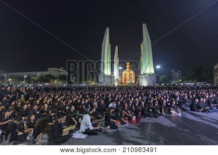 BANGKOK THAILAND - OCTOBER 26: Unidentified mourners in black sit and watch the royal activities for the cremation of Rama 9 the former king next to Democracy Monument in Bangkok Thailand on October 26 2017.