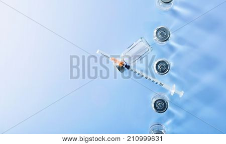 Row Of Vials And Syringe On Blue Table Top View