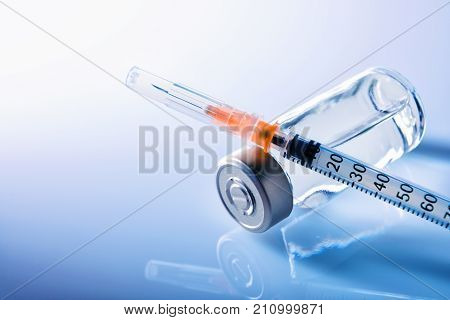 Vials And Syringe On Blue Table With Blue Background Elevated