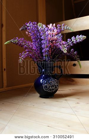 Bouquet of lupins in a blue vase on a wooden floor