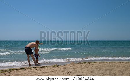 Father And Son On The Beach On A Clear Day. People Have Fun In The Fresh Air. The Concept Of A Summe