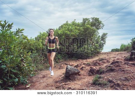 Young Sportswoman Cross Country Running On Dirty Rocky Footpath In Mountains In Summer. Fit Girl Jog