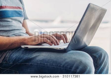 Young Man Using Laptop In Airport Terminal
