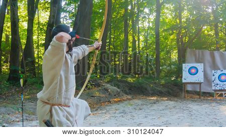 Medieval Male Archer Shooting Targets With Wooden Bow At Historical Festival. Archery And Medieval C